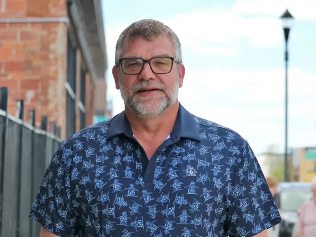 marc lauzier A man with gray hair, beard, and glasses stands outside, wearing a blue patterned polo shirt. Brick buildings and a lamp post are in the background. Liberals Canada Politics